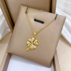 Luxurious gold four-leaf clover necklace with sparkling diamonds on a silk display