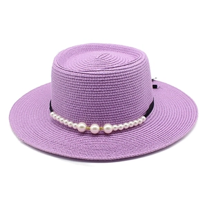Dettaglio cappello di paglia lavanda con nastro di seta nera e decorazione di perle bianche