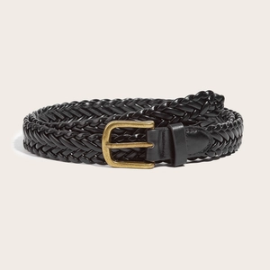 Retro black woven leather belt for women with a vintage brass buckle on beige background
