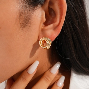 Close-up of gold irregular geometric interlaced hoop earrings on model ear