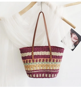 Detailed macro view of woven straw tote bag with rainbow stripes and brown leather handles