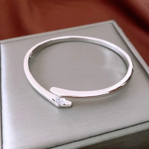Detail of silver bypass bangle with round-cut cubic zirconia on a red satin backdrop
