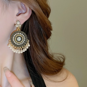 Close-up of ethnic pearl and rhinestone drop earrings on model in profile view