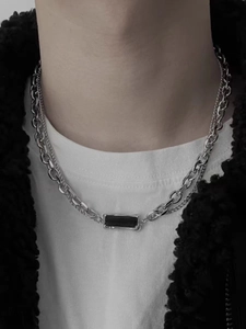 Close-up of men's silver double-layer chain necklace with a black rectangular pendant