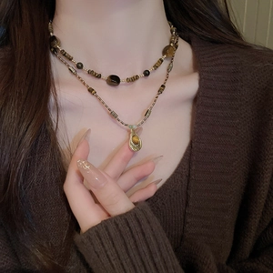 Gros plan sur collier double rang en œil de tigre avec pendentif goutte d'eau dorée