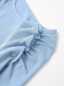 Dettaglio del tessuto a maglia azzurro con nodo elegante e bottone in tessuto