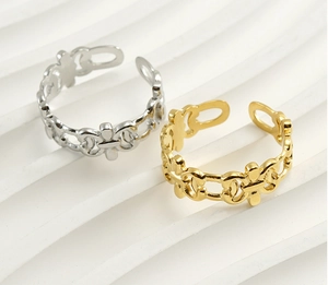 Detail of hollow chain link rings in gold and silver finishes on a wavy textured surface