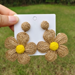 Macro shot of large hand-woven raffia flower earrings in brown and yellow tones