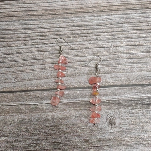 Detail of pink natural crystal stone bead earrings with silver hooks on wood background