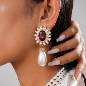 Détail d'une boucle d'oreille fleur rétro avec gemme rouge et grande perle goutte blanche