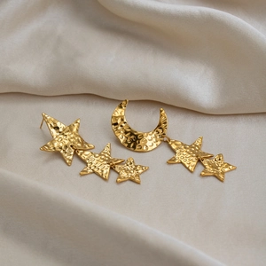 Detail view of asymmetric hammered gold star and moon drop earrings in stainless steel