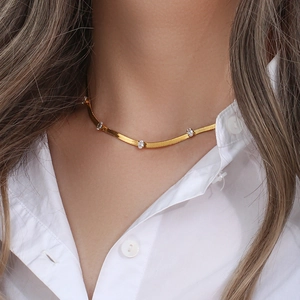 Close-up of golden blade chain necklace with transparent zircons on white shirt