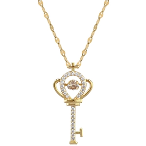 Elegant gold key necklace with dancing stone and pavé zircon on white background