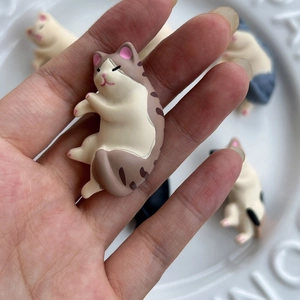 Cute brown and white cat hair clip doll accessory held over white ceramic plate