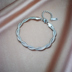 Detailed macro view of the silver twisted stainless steel chain bracelet on silk fabric