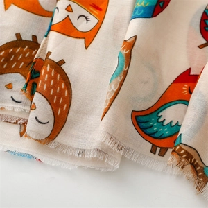 Detail shot of cotton-linen feel scarf showing colorful cartoon owl prints and fringe texture