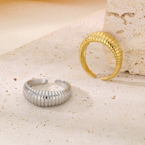 Dettaglio degli anelli a croissant in oro e argento su un piedistallo di pietra beige