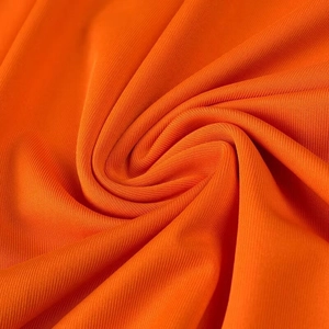 Vue macro du tissu en maille orange montrant une élasticité fine et un lustre doux sur la robe