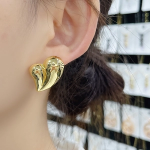 Polished 18K gold heart stud earrings shown worn on ear for a modern minimalist look