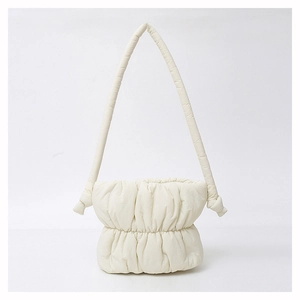Detail view of a creamy white padded cloud bucket bag showing soft pleated nylon texture