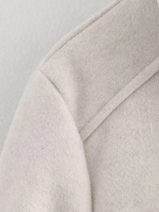 Detailed close-up of cream wool blend jacket shoulder seam and thick woven fabric texture