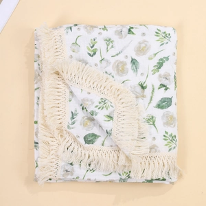 Detail of baby swaddle blanket with elegant floral print and delicate tassel edges