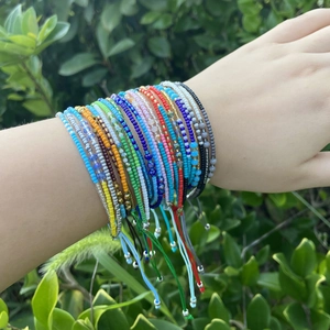 Close-up of colorful bohemian seed bead bracelets on a wrist against green leaves
