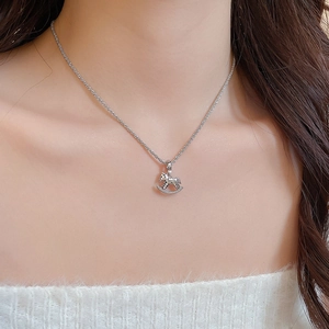 Detail of silver rocking horse pendant with sparkling crystals on a delicate chain