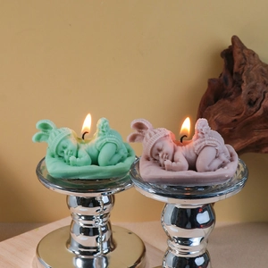 Sleeping baby aromatherapy candle in mint green and dusty pink on a silver candle holder