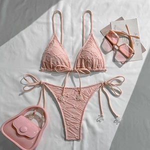 Detail of pink smocked bikini fabric with delicate white flower bead charms and tie-side