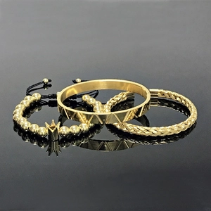 Macro shot of 3-piece gold bangle set with crown charm and woven textures on mirror