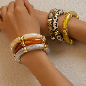 Detail of bohemian acrylic bangle set with leopard print and marble textures on a model