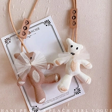 Detailed close-up of brown and beige fabric bear charms with mesh bows and wooden tags