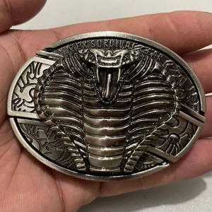 Detail of silver cobra belt buckle with survival gear engraving and snake relief