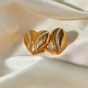Detailed view of 18k gold teardrop earrings with crystals on white silk background