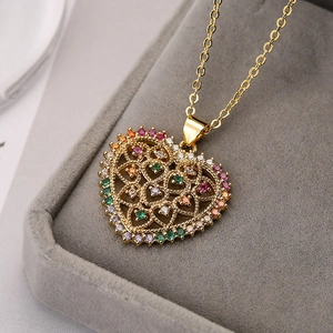 Goldene hohle Herz-Halskette mit bunten Zirkonias auf grauem Samt-Schmuckkästchen