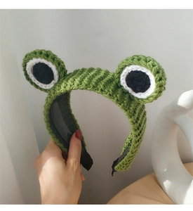 Detail of green handmade crochet frog headband showing knit texture and big cartoon eyes