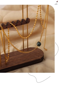 Close-up of golden beaded titanium necklace with faceted green agate pendant on display