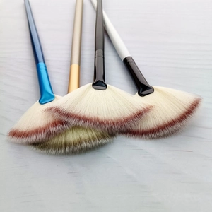 Dettaglio di quattro pennelli a ventaglio con manici colorati e setole sfumate morbide