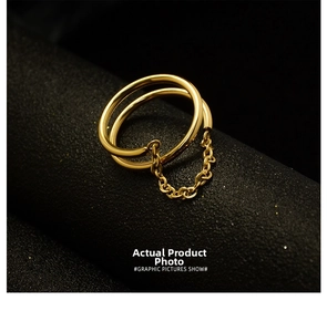 Macro detail of gold double-layered open ring with delicate chain on a black jewelry stand