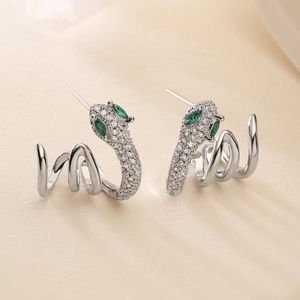 Minimalist snake-shaped silver earrings with sparkling white zircons and green gem eyes