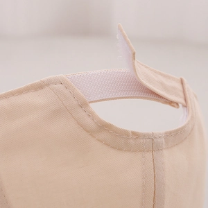 Détail de la sangle velcro réglable et du tissu en coton sur un chapeau bébé beige