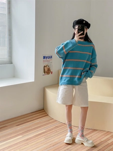 Close-up of blue knit sweater with orange stripes and floral print socks for autumn style