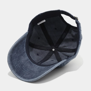 Detailed interior of a navy washed denim baseball cap with adjustable brass buckle
