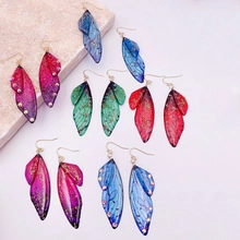 Macro view of gradient butterfly wing earrings with fine textures and micro rhinestones