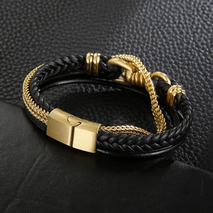 Detail of multi-layer braided leather bracelet with golden magnetic clasp on black surface