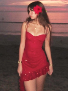 Elegant red sequin camisole dress with ruffle hem, shown on beach during golden hour