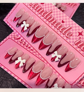 Detail of red French press-on nails with 3D bows and pearls on a size M display card