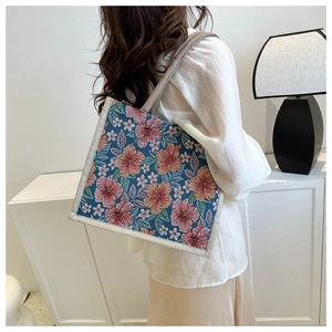 Detalle del bolso tote de lona jacquard con flores y asas crema sobre fondo azul