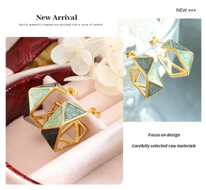Macro detail of hexagonal titanium earrings with green marble enamel and gold trim